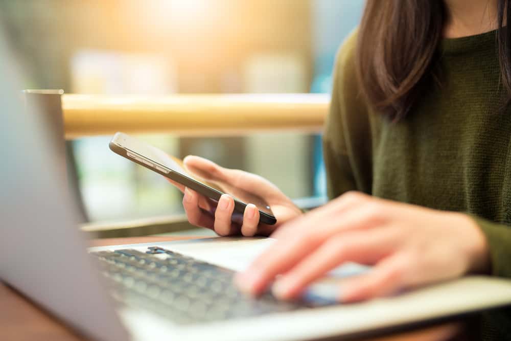 Woman connecting cellphone and laptop computer 1